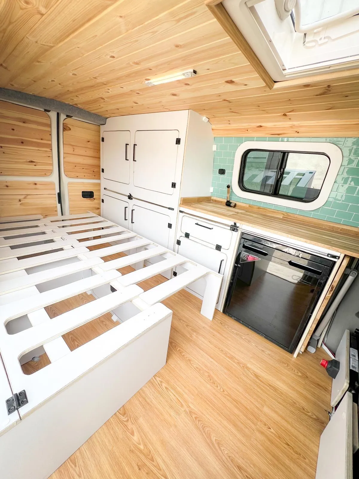 Interior de una furgoneta mediana camperizada con cama, almacenamiento y cocina
